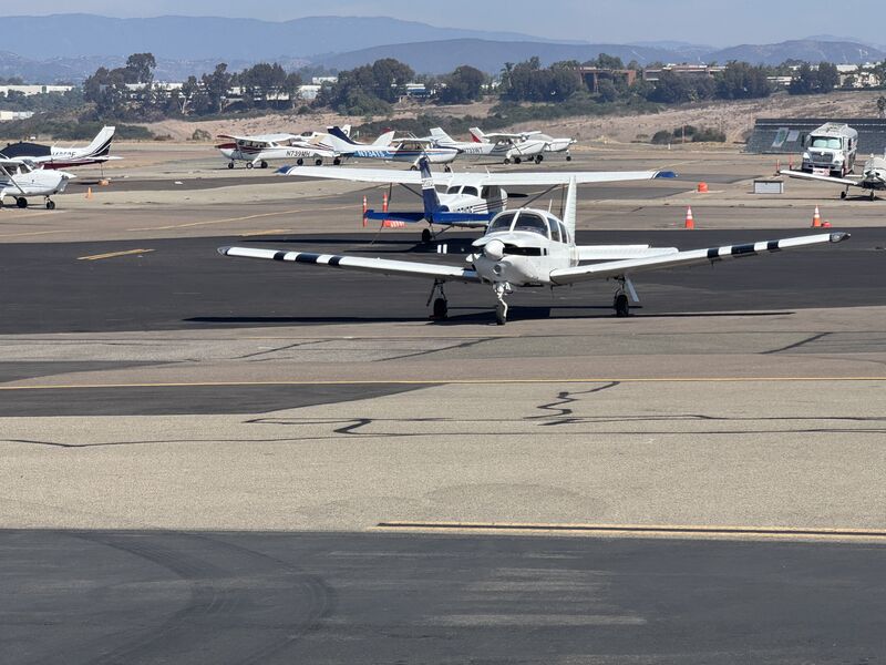 The Arrow on the ramp among parked aircraft, with hills in the distance