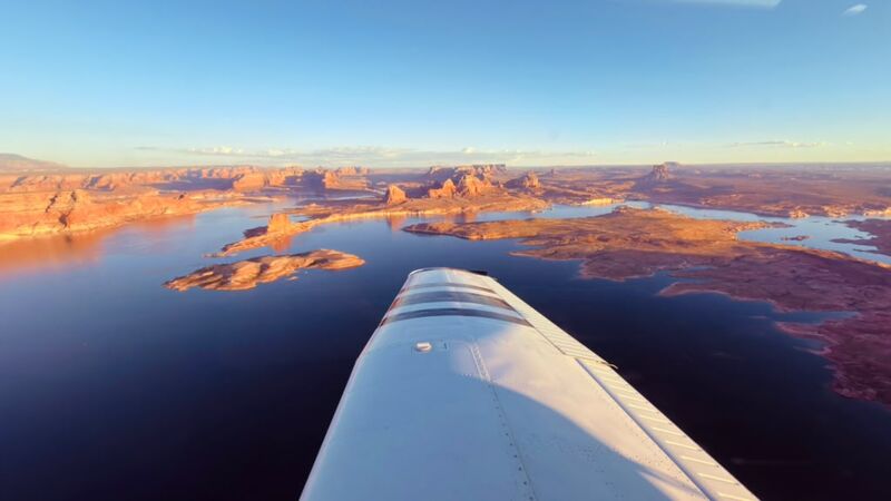 View along the wing over Lake Powell, with red rock buttes and still water in the evening light